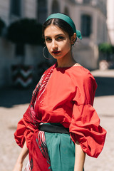 Young spanish woman in a red blouse and green pants. Fashion latin look. Woman walking in old town...