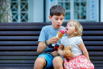 Big brother giving his ice cream to little sister outdoor