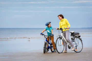 Young mother with her little son riding bicycles on beach - 228510277