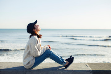 海沿いで空を眺める20代女性