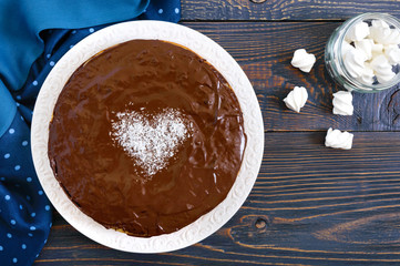 A big festive chocolate cake, a heart of coconut in the middle. The top view