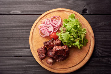 Top view of plate of sliced sausage decorated with aromatic herbs. Sausage on wooden catering platter, flat lay of meat delicatessen