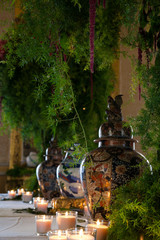 Expensive china, chinese urn with lid on set table with candles and green plant. 