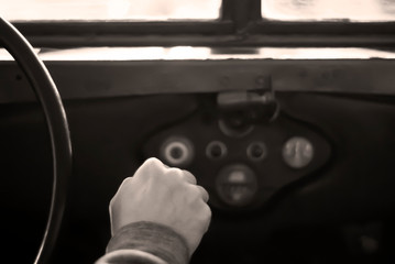 driving a vintage army off-road vehicle; only the driver’s hand on the gear lever and a steering...