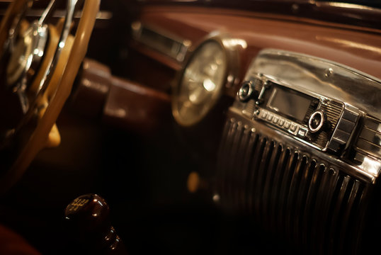 Blurred warm background - a fragment of the interior of a vintage car, focus on the handle of the radio