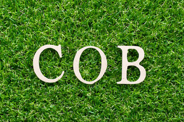 Wood alphabet in word COB (abbreviation of close of business) on artificial green grass background
