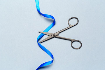 Grand Opening illustrated with  scissors and a blue ribbon on a gray background