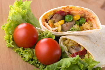 Delicious burrito with vegetables at wooden background.