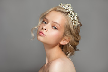 Beautiful blond girl in the image of a bride with a tiara in her hair. Picture taken in the studio on a gray background. Beauty baby face. Wedding image. © hamara