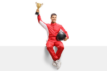 Winner racer in a suit holding a gold trophy cup and sitting on a panel © Ljupco Smokovski