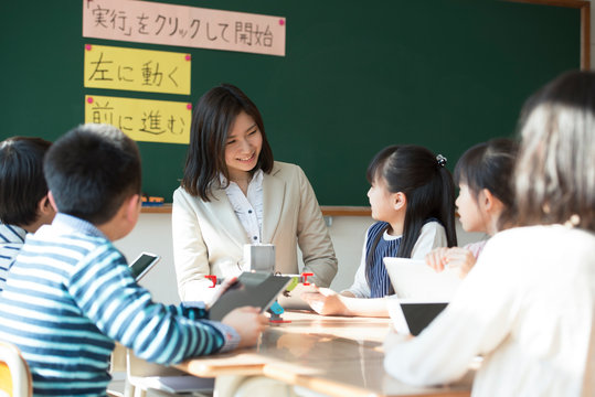 プログラミングを教える先生と小学生