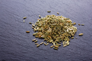 Fototapeta na wymiar Essential oil of fennel seeds on a dark stone background
