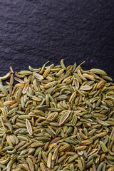 Essential oil of fennel seeds on a dark stone background