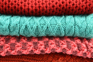 Knitted red, orange, green scarves. Collection of woolen clothes.