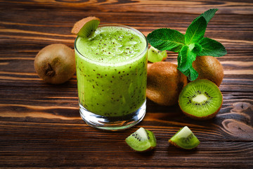 Healthy fresh kiwi smoothie in glass on a wooden background