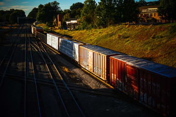 A shadowy view of railroad train cars on an urban railroad track rolling towards the horizon. Copy space.
