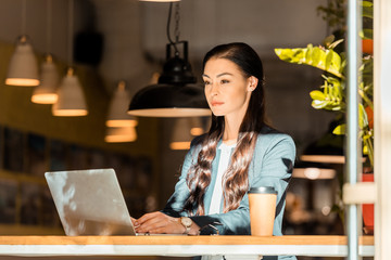 attractive brunette freelancer working with laptop at coffee shop