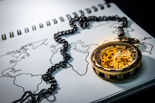 Gold pocket watch on world map outline sketch on paper page of notebook. Travel around the world. Global business concept