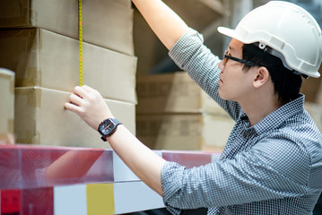 Male worker hand using tape measure for measuring dimension of product in cardboard box. Shopping...