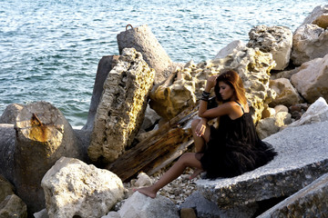 
Cute girl posing on rocky boulders on the seashore