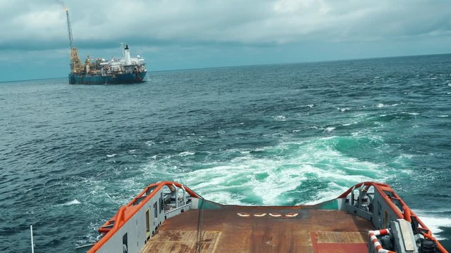 Anchor-handling Tug Supply AHTS vessel during dynamic positioning DP operations near FPSO tanker. Vessel is doing static tow tanker lifting. Ocean tug job.