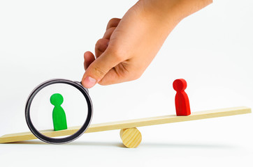 wooden figures of people. rivals in business stand on the scales. trial. conflict. victory and...