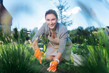 Cheerful woman. Beautiful cheerful green-eyed woman feeling amazing while working in garden and...