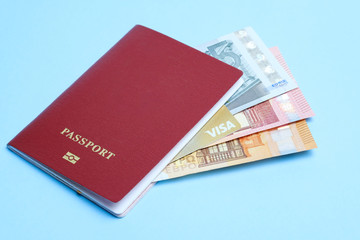 Euro banknotes and VISA card enclosed in a foreign passport isolated on a blue background. Travel to Europe.