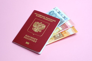 Euro banknotes and VISA card enclosed in a foreign Russian passport isolated on a pink background. Travel to Europe.