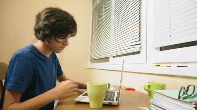 boy teenager poured tea on the laptop. doing homework, online learning, 4k close-ups,