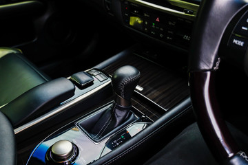 The black leather interior of a luxury European vehicle. Center console with brushed nickel shift...