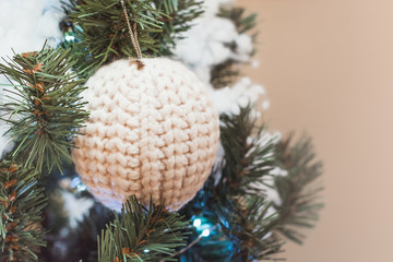 Christmas tree with knitted white ball as decor with copy space on blurred bokeh. Close up.