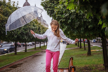 School gir under an umbrella walking in the rain in the city alley.