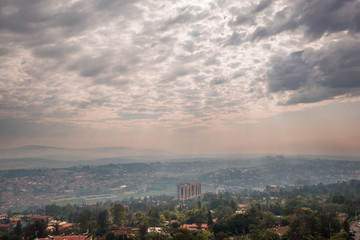 Fototapeta premium Sunlight breaks through the clouds over the hills of Rwanda that stretch into the distace