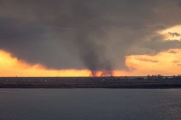environmental pollution problem of fire on dry grass with smoke onthe horizon inflated by a strong...