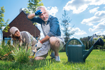 Mopping brows. Bearded grey-haired man mopping his brows after working hard near garden bed with...