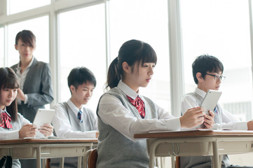 教室で授業を受ける学生と女性教師