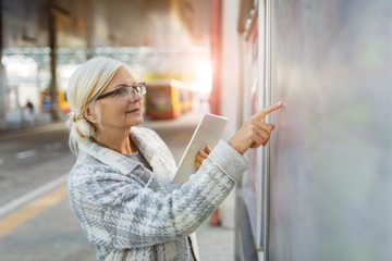 Senior woman using tablet, while waiting for the bus
