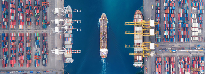 Aerial view panoramic oil tanker moving pass sea port warehouse and container ship. 