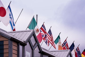 Flags of the world on top of a restaurant in Alaska USA. Colorful symbols with grey sky background.  