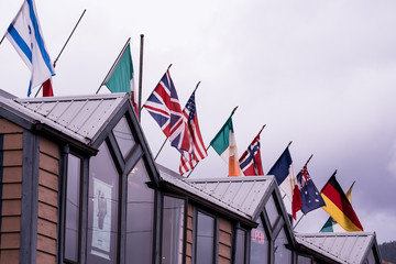 Flags of the world on top of a restaurant in Alaska USA. Colorful symbols with grey sky background.  