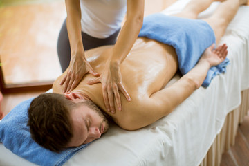 Fototapeta na wymiar Young man having massage in the spa