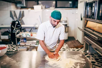 Wandcirkels plexiglas Man werkt in het restaurant en maakt pizza bij de pizzeria. © OscarStock