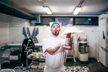 Selbstklebende Fototapeten Man works in the restaurant making pizza at the pizzeria. © OscarStock