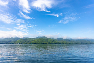 Landscape of the mountain and river with blue sky in the morning. View of the mountain with blue sky at Srinakarin Dam , Kanchanaburi province , Thailand.