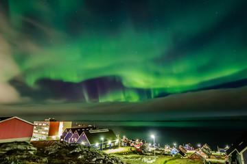 Green bright northern lights hidden by the clouds over the Inuit village at the fjord, Nuuk city, Greenland © vadim.nefedov