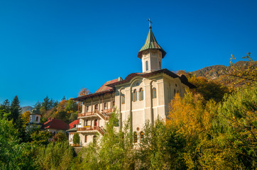 Fototapeta na wymiar Turnu Monastery, Cozia Mountain, Romania. The monastery is located near Calimanesti Caciulata, Valcea county. It is surrounded by a wood fence. The photo was taken in autumn.