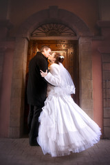 The bride and groom kiss on the old street of the city.