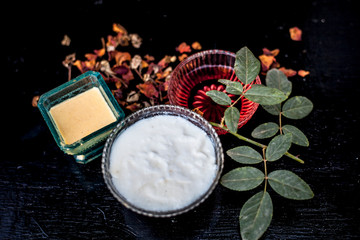 Close up of herbal and ayruvedic face  pack of rose or Rosa or Rosaceae or gulab with its extracted rose water in a glass bowl with gram flour and yogurt on wooden surface,Top shot view.