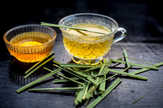 Close Up Of Iced Lemon Grass Tea In A Transparent Cup On Wooden Surface With Raw Lemon Grass Green Tea In A Cup And Sugar In A Clay Bowl With Ice Cubes In The Cup And A Piece Of Ginger And Honey.